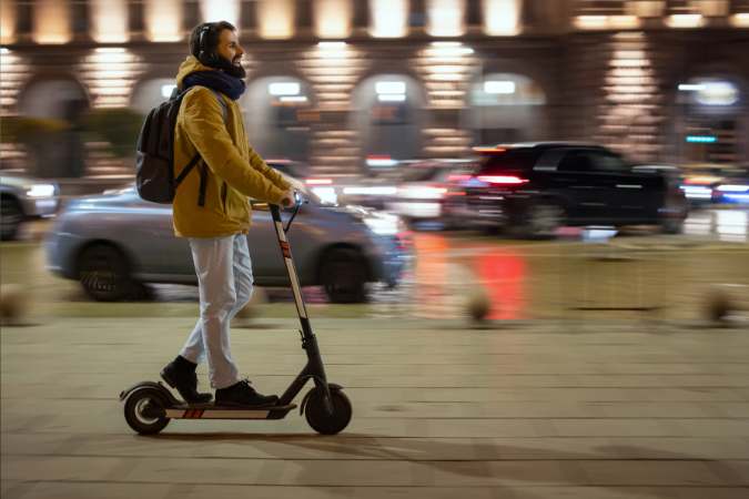 A young man is riding his electric scooter on the street